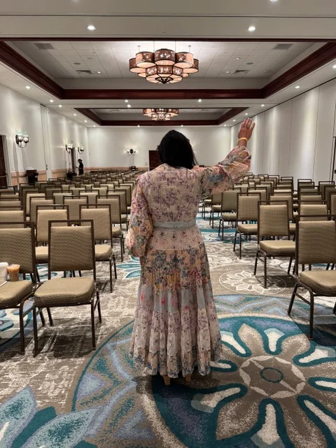 Melanie Cox in an event room with her hand raised