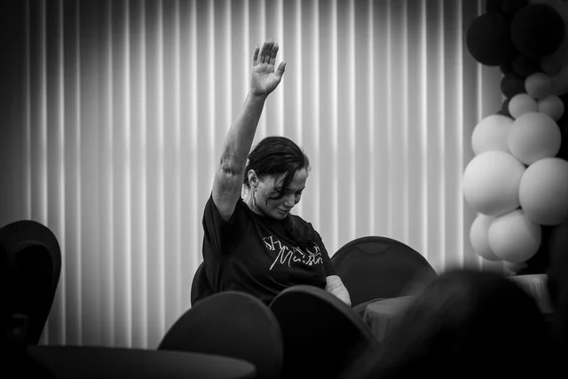 Melanie Cox with her hand raised during a gathering